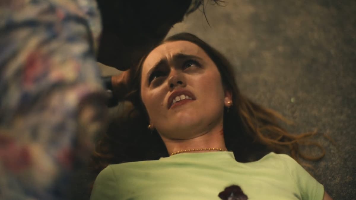 a still of a woman on the ground, bleeding from the chest