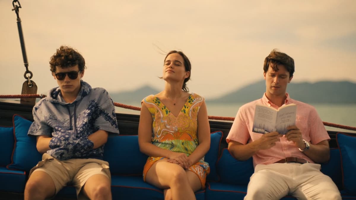 a boy in glasses, a girl with her eyes closed, and a man reading a book on a boat