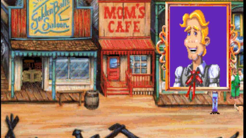 A blonde cowboy-looking man speaks to another on the street of a classic Western-style town. 