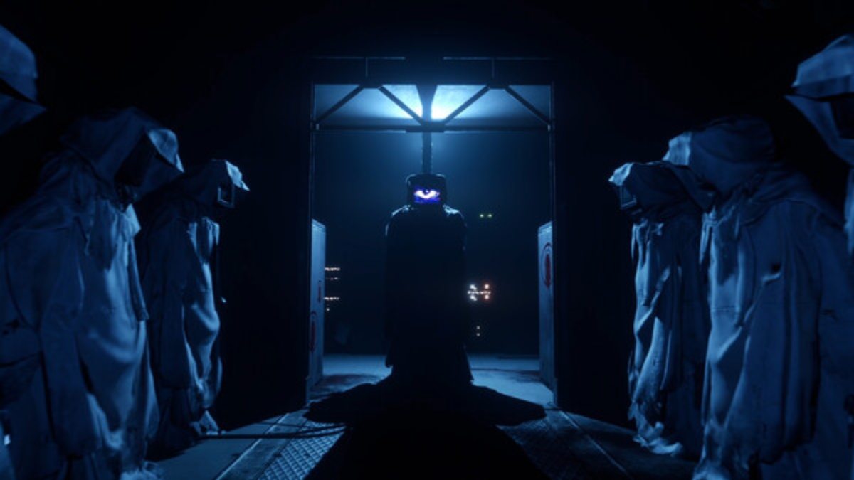 Harley Sawyer's eye piercing through the darkness with security bots lined up on either side of him