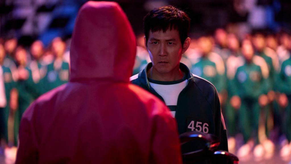 Gi-hun looking at a guard wearing pink in Squid Game