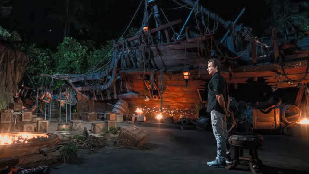 Jeff Probst standing in front of a shipwreck at tribal council in survivor