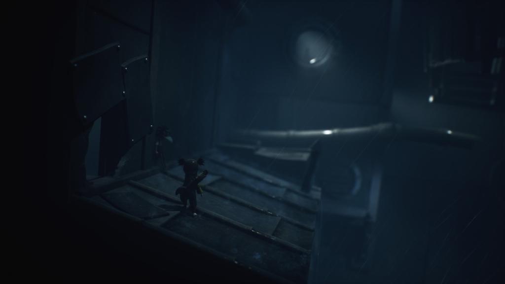 Standing on a roof, next to a hole in the metal wall, away from a giant pipe