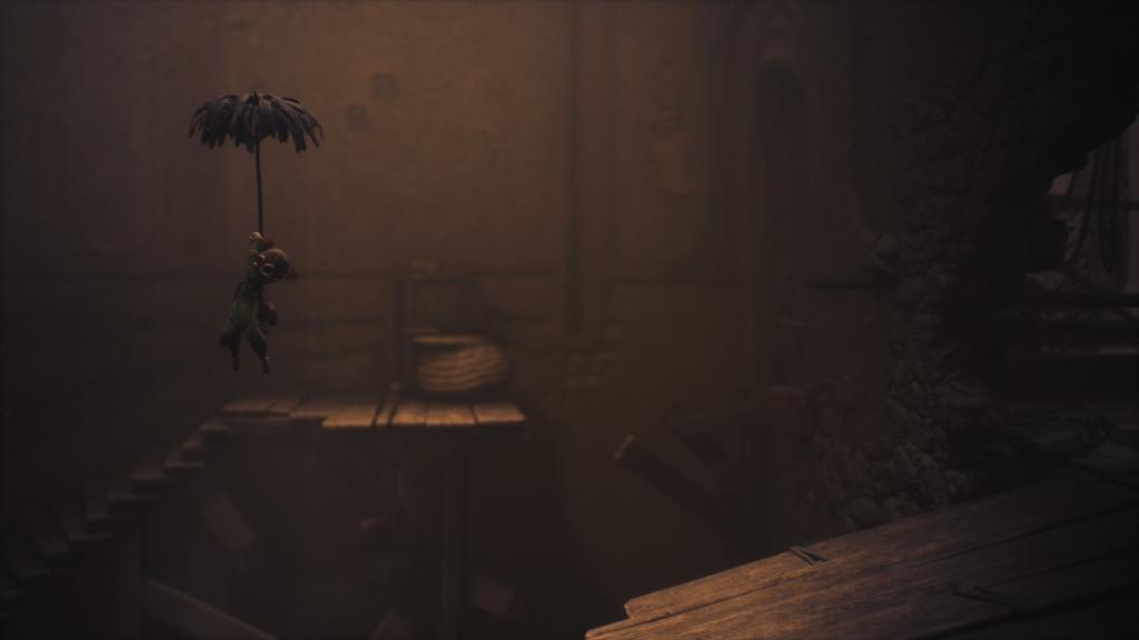 Using the umbrella to float with the third doll out of focus in background, atop a spiral staircase