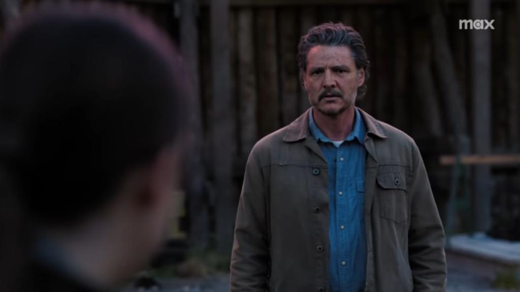 Pedro Pascal playing as Joel Miller in TLOU with back of Ellie's head out of focus in foreground