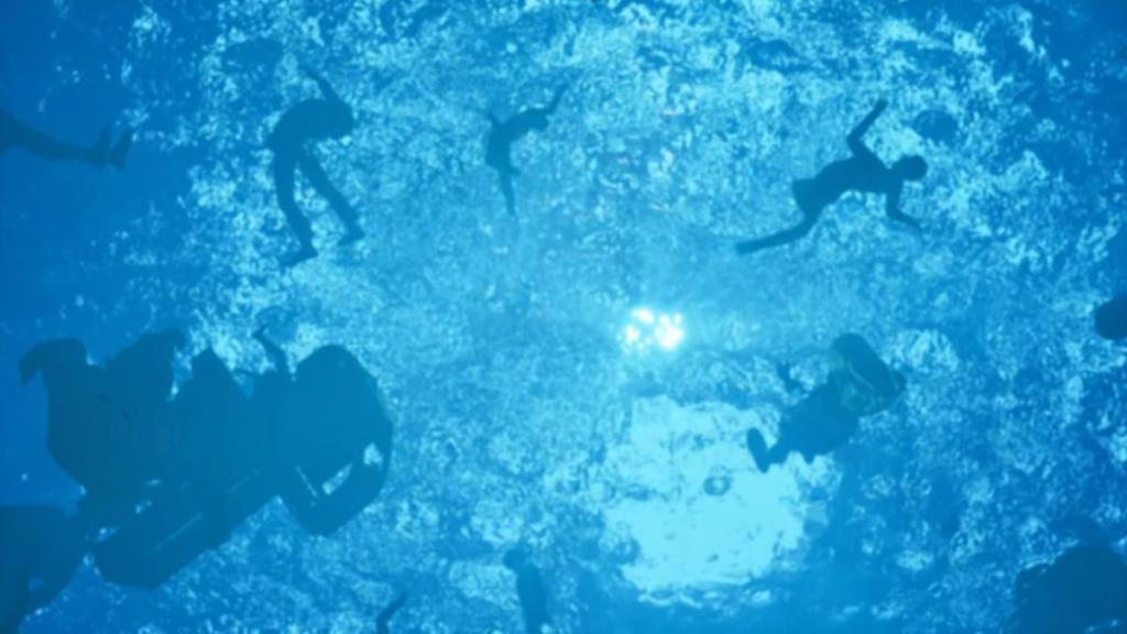 A shot as protagonist sinks in the ocean with bodies floating past them towards the surface