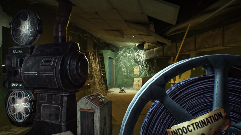 Holding a film reel with indoctrination on it and Ink Blaster standing in background under spotlight